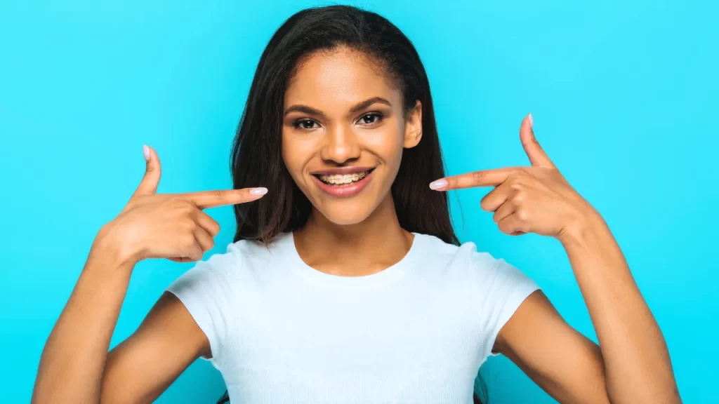 A woman posing pointing at her braces
